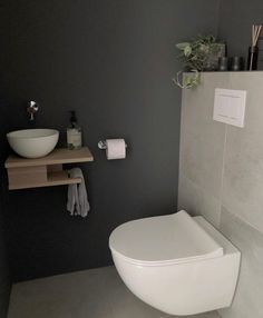 a white toilet sitting in a bathroom next to a wooden shelf with a bowl on it