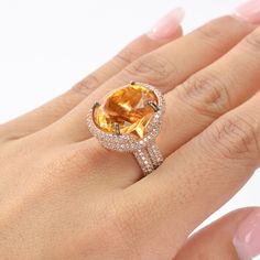 This exquisite ring features a stunning Citrine as the center stone, radiating vibrant hues of golden yellow. The Citrine is complemented by an array of White Zircon accent stones, adding a touch of brilliance and sparkle to the piece. The design showcases a luxurious rose gold-plated band, enhancing the warm tones of the Citrine. The intricate setting highlights the gemstone's natural beauty, making it a perfect statement piece for any occasion. This piece is inspired by the Art Deco era, known Luxury Yellow Oval Rings, Luxury Citrine Topaz Ring With Gemstone Accents, Luxury Citrine Topaz Ring With Accent Stones, Luxury Topaz And Citrine Ring With Accent Stones, Elegant Yellow Topaz Ring With Gemstone Accents, Citrine Center Stone Topaz Ring, Oval Yellow Diamond Promise Ring, Fine Jewelry Yellow Round Diamond Ring, Fine Jewelry Yellow Topaz Ring With Halo Setting