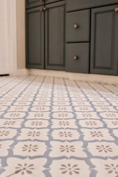 a white and blue tiled floor in a bathroom next to cabinets with drawers on each side