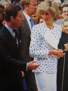 two men and a woman standing next to each other in front of a group of people