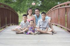 a family sitting on a bridge posing for a photo with their two children and one adult