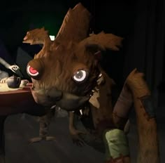 an animated creature with big eyes sitting at a table next to another character in a video game