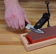 a person using a knife sharpener on a piece of wood