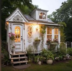 a small white house with potted plants outside