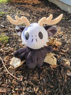 a stuffed animal with antlers on it's head sitting in the dirt outside