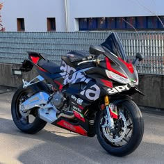 a red and black motorcycle parked in front of a building