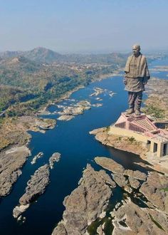 there is a statue on top of a hill overlooking the water and land below it