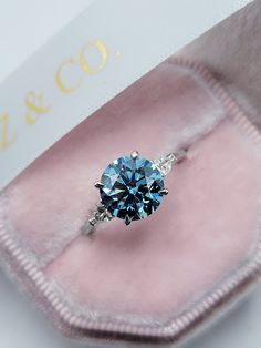 a blue diamond ring sitting in a velvet case