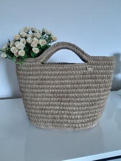 a straw bag with flowers in it sitting on a white countertop next to a wall