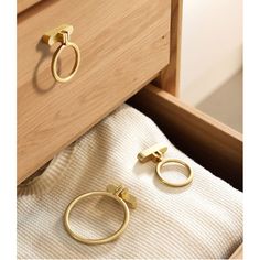 two gold rings are sitting on a towel in front of a drawer with white towels