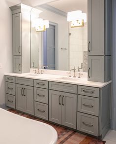 a bathroom with double sinks and large mirrors on the wall, along with a bathtub