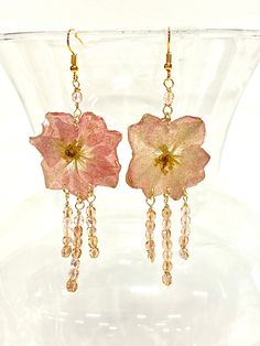 Step into a world where nature meets whimsy with these enchanting handmade statement floral earrings! Each pair is a labor of love, meticulously crafted with genuine dried and pressed flowers, carefully selected to capture the essence of spring.  The flowers are delicately encapsulated in uv resin, creating a mesmerizing display of color and texture that's guaranteed to turn heads. But that's not all - we've sprinkled just a touch of art glitter into the resin mixture, adding a subtle sparkle that catches the light with every movement. It's like wearing a piece of magic on your ears! And let's talk about those dangles - each earring features hand-wrapped Austrian crystals that dance and shimmer with every step you take. They add a touch of glamour and sophistication to the natural beauty o Bohemian Drop Earrings With Pressed Flowers, Bohemian Dangle Earrings With Pressed Flowers, Pink Bohemian Jewelry With Pressed Flowers, Bohemian Pink Jewelry With Pressed Flowers, Whimsical Flower-shaped Handmade Earrings, Bohemian Flower Earrings With Birth Flower Details, Bohemian Flower Earrings With Birth Flower, Pink Flower-shaped Earrings With Pressed Flowers, Pink Flower Earrings With Pressed Flowers