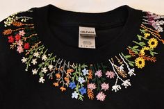 a close up of a shirt with flowers on the front and neckline that has been embroidered onto