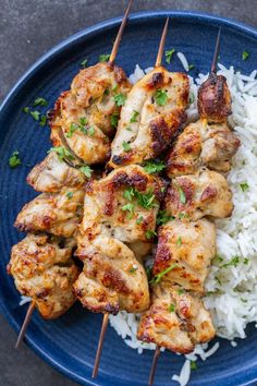 chicken skewers with white rice on a blue plate