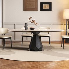 a dining room table with chairs and a vase on top of it in front of a white wall