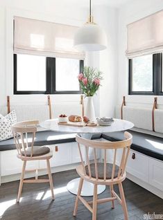 an open magazine with two chairs in front of a table and flowers on the counter