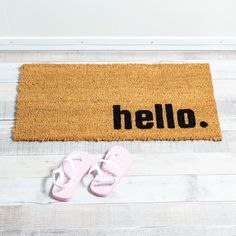 a pair of pink slippers sitting on top of a door mat that says hello