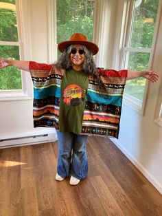 Iconic 70s band America recycled t-shirt upcycled into a beautiful loose fitting poncho top.  This top is one size fits all.  The poncho is constructed with a patchwork of southwestern desert themed cotton fabric on the sides.  The chest is 40 inches across, 80 inches around and it is 26 inches long.  The arm holes are 8.5 inches wide.  Machine wash cold gentle cycle tumble dry low. Oversized Bohemian Patchwork Tops, Oversized Hippie Festival Tops, One Size Festival Tops For Fall, Bohemian Cotton Tops One Size, Oversized Cotton Bohemian Poncho, Oversized Hippie Poncho For Fall, Oversized Multicolor Poncho For Festival, Upcycle Dress, America Band