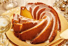 a bundt cake with frosting on a plate next to a glass of wine