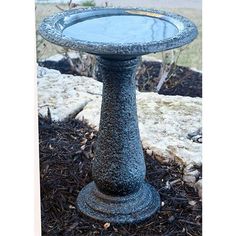 a bird bath sitting on top of a pile of mulch