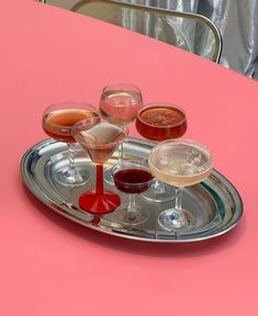 several glasses of wine are on a silver tray