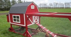 a red chicken coop in the middle of a grassy field