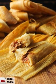 tamales cut in half on a wooden cutting board with other food items behind them