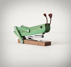 a green stapler sitting on top of a wooden block