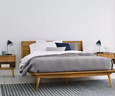 a bed sitting on top of a white floor next to two nightstands with lamps