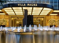 the front entrance to villa magnaa at night with water fountain in foreground and lights on