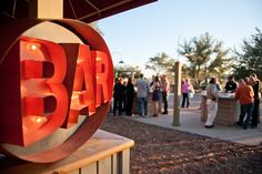 a group of people standing around a bar sign