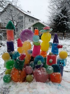 a pile of gummy bears sitting on top of snow covered ground next to a house