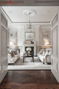 a living room filled with furniture and a chandelier hanging from the ceiling over a fire place