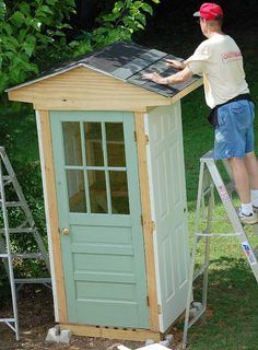 a man standing on top of a ladder next to a small green shed with a solar panel roof