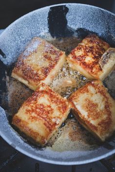 four pieces of bread cooking in a pan on the stove top with oil and seasoning