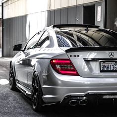 the rear end of a silver car parked in front of a building