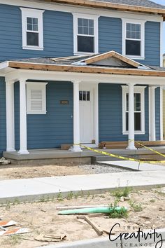 a blue house with white trim on the front door and windows is being renovated by a construction worker