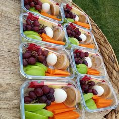 several plastic containers filled with assorted fruits and veggies on top of a wicker table