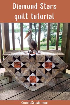 a pelican sitting on top of a table next to a piece of quilt