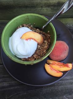 a bowl filled with yogurt, granola and peaches on top of a black plate