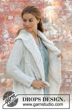 a woman is standing in front of a brick wall wearing a white cardigan sweater