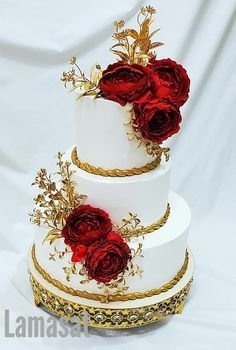 a three tiered cake with red roses on top and gold trim around the edges