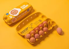 an egg carton with six eggs in it next to two eggs on a yellow background