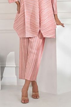 Rose metallic long line top with pleat detail all over and asymmetric hem. Paired with pleated straight fit pant. - Aza Fashions Elegant Pink Long Pants Set, Elegant Pink Sets With Long Pants, Chic Pleated Spring Sets, Pleated Sets For Spring, Elegant Spring Sets With Ankle-length Pants, Elegant Pleated Spring Sets, Elegant Pants With Accordion Pleats For Spring, Elegant Spring Pants With Accordion Pleats, Elegant Pink Wide Leg Sets