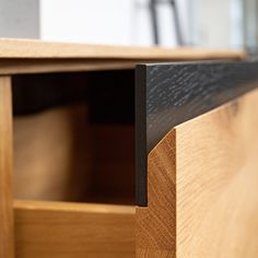 a close up view of a wooden cabinet with black metal handles and wood grain detail