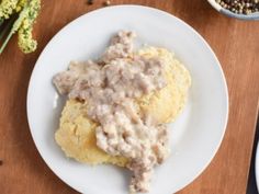 biscuits and gravy on a plate next to a bowl of broccoli