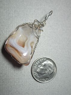 Lace Agate Pendant Wire Wrapped in .925 Sterling Silver Round Wire This beautiful stone provides a swirled blend of clear and white with orange-brown accents around its perimeter, also displaying a very fine orange-brown druzy center pocket. Quite versatile; it matches well with many colors of clothing, provides a nice contrast with darker shades, and elegance with lighter colors; probably best worn with black, white, brown tone and earth tone colors, but wears reasonably well with most colors. Elegant Agate Jewelry With Large Stone, Elegant Wire Wrapped Chalcedony Jewelry, Marble Agate Jewelry As A Gift, Marble Agate Jewelry Gift, Marble Colored Agate Jewelry With Natural Stones, Marble Agate Jewelry, Earth Tone Colors, Brown Tone, Silver Lace