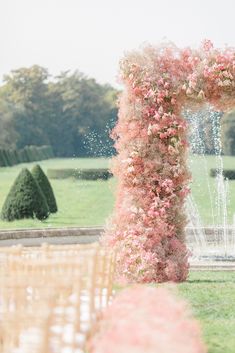 an outdoor wedding ceremony setup with pink flowers and water spouting from the top