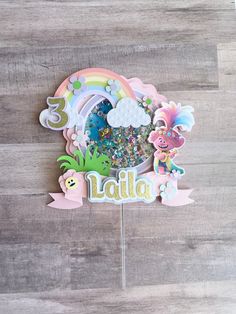 there is a cake topper that says latila on it and has an image of a rainbow