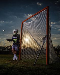 a lacrosse goalie standing in front of the net with his ball and glove on